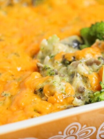 Broccoli cheese casserole final image in tan casserole dish with contents being scooped out.