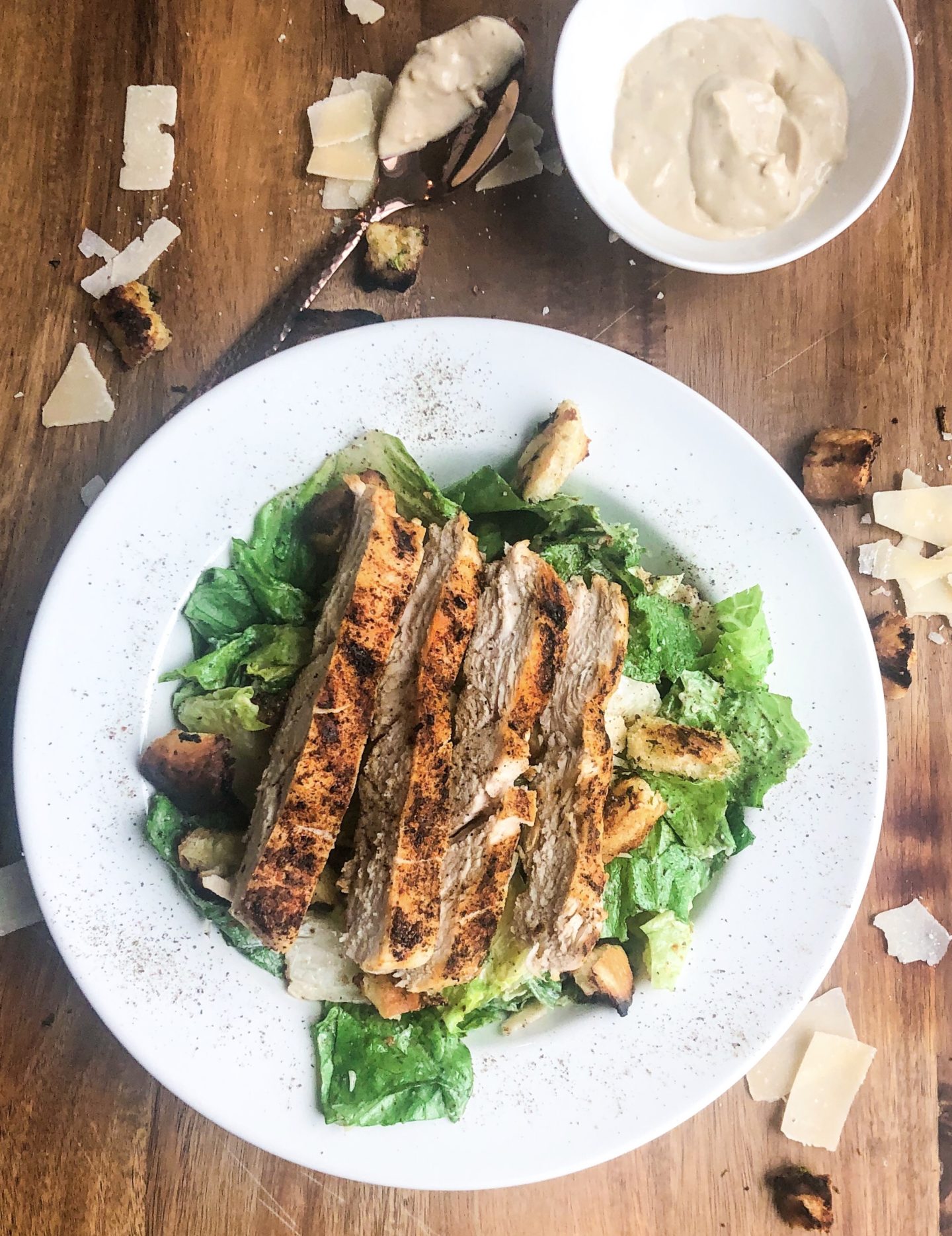 overhead view of plated grilled chicken caesar salad with a side of homemade dressing