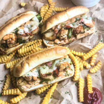 Three Seafood Cheesesteaks with remoulade sauce, veggies and french fries.