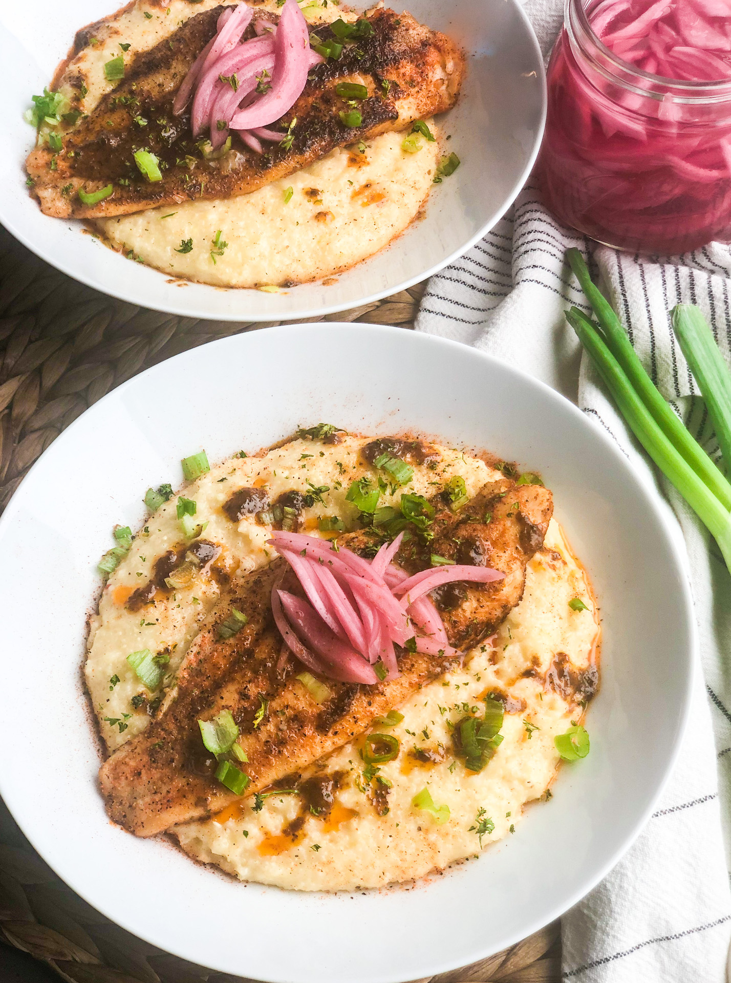 two plates of fish and grits topped with pickled onions