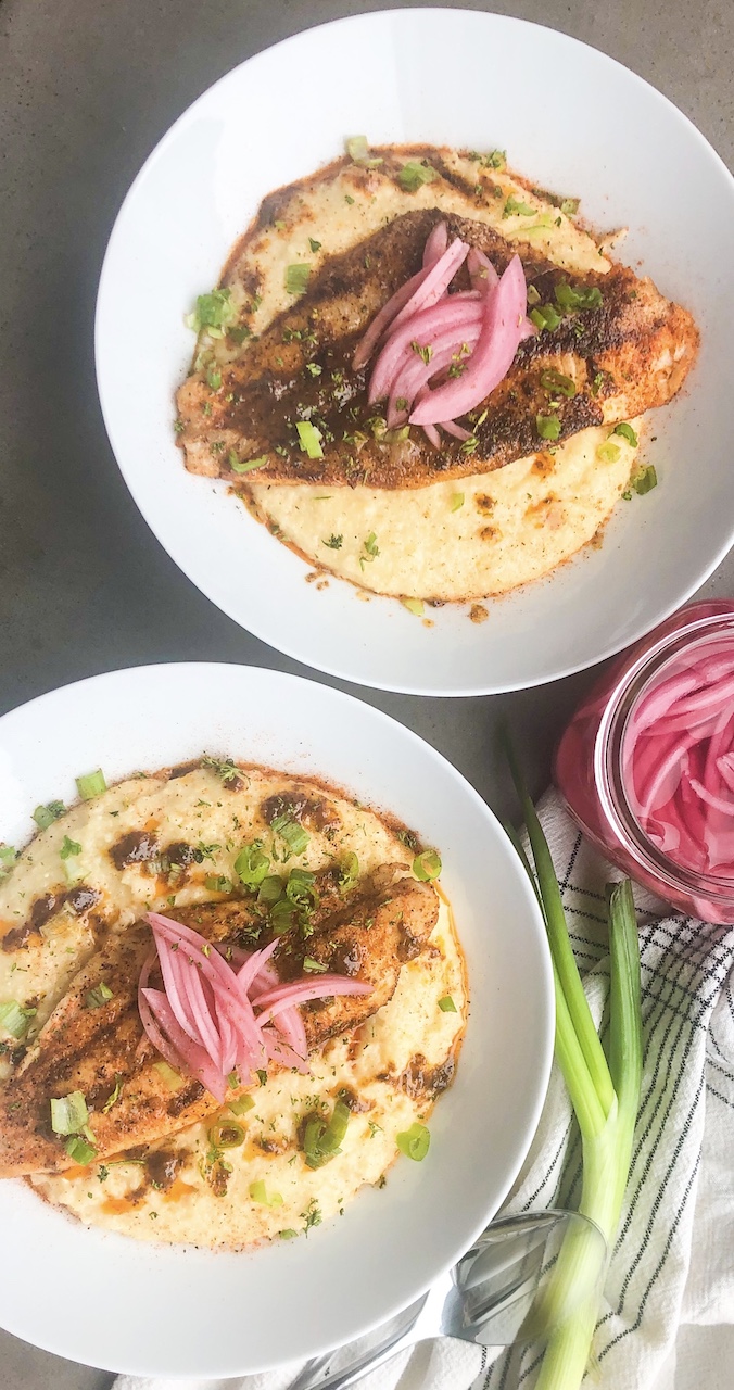 two plates of fish and grits topped with pickled onions