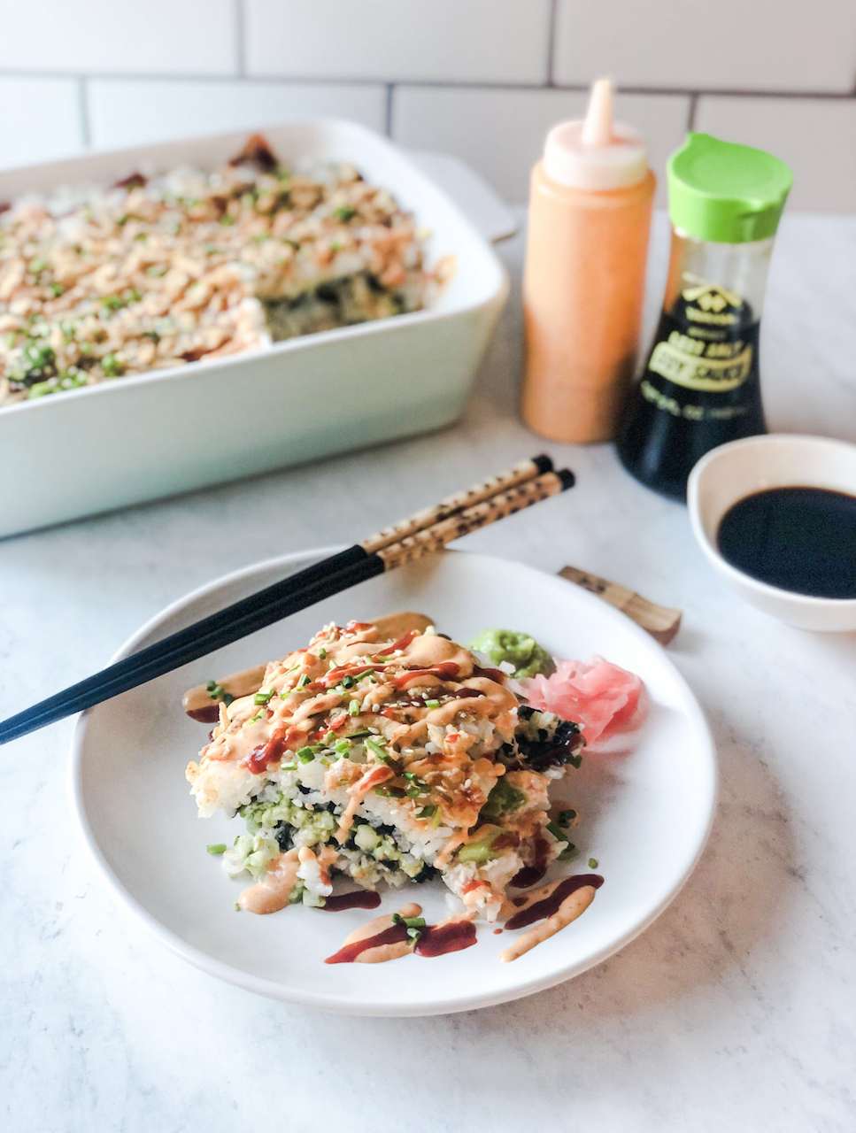 plated crab sushi bake with chopsticks on the side, and soy sauce and the casserole dish in the background