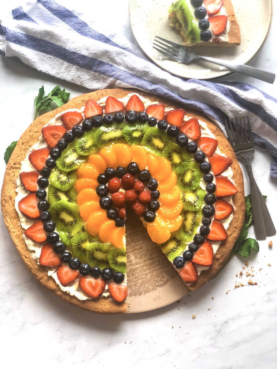 a sugar cookie fruit pizza with a slice cut out and plated 