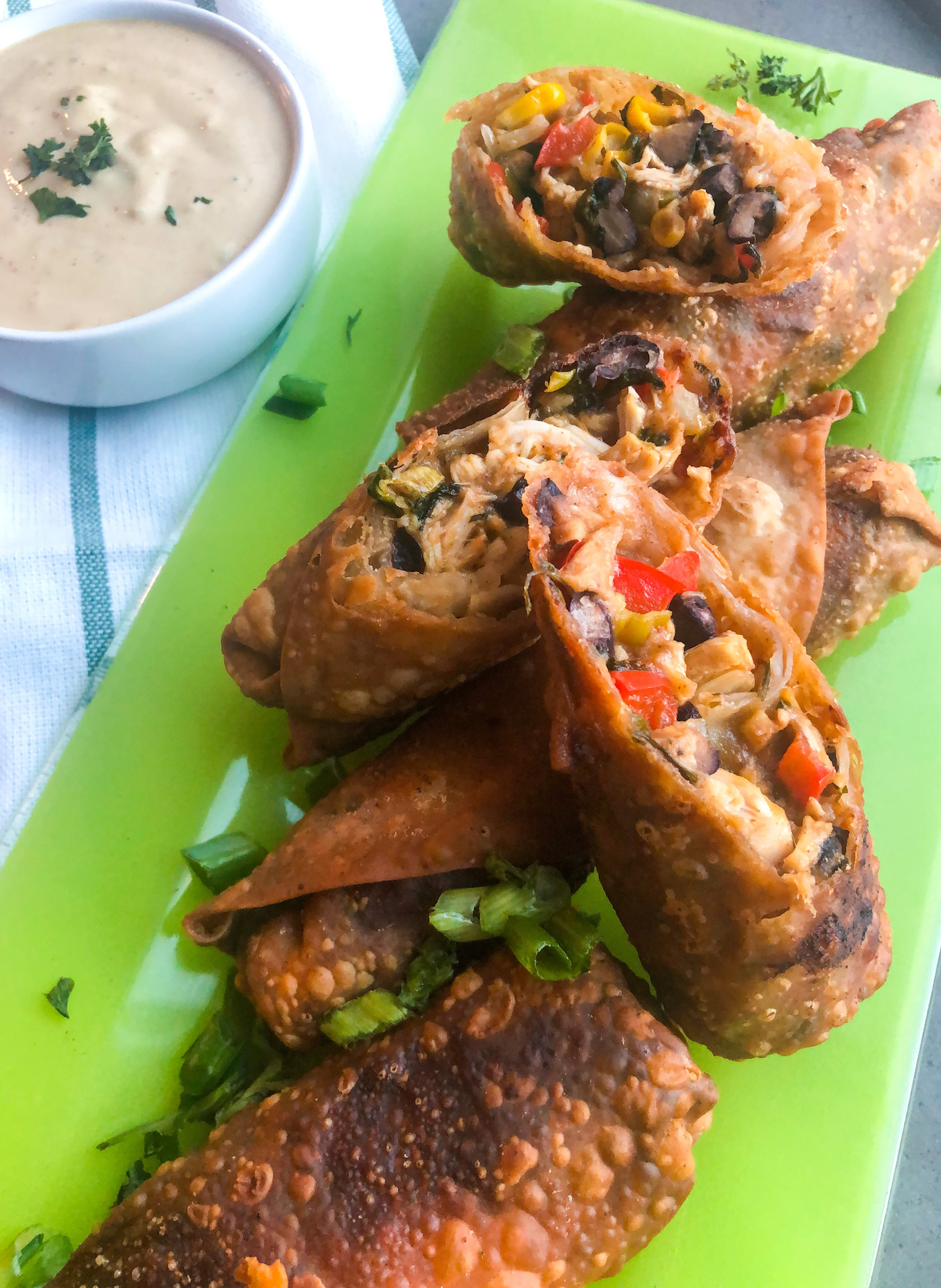 Green rectangular plate with crispy southwestern egg rolls .