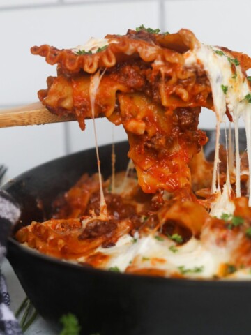 Featured image of lasagna being pulled out of black cast iron with cheese pull.
