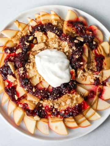 Sliced Apples topped with peanut butter and jelly, drizzled with granola.