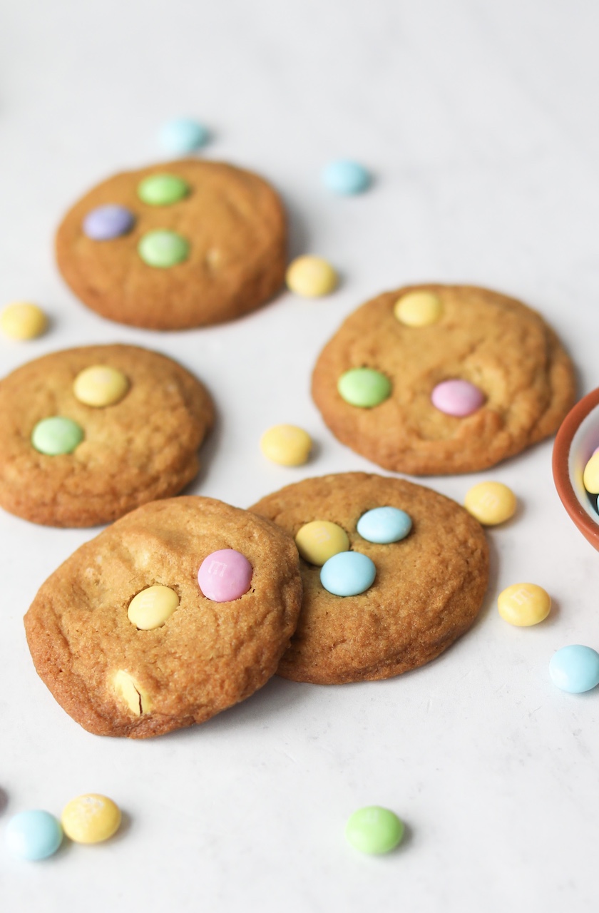 Five flat sugar cookies with Easter themed M&M's and loose M&M's around the cookies for decor.