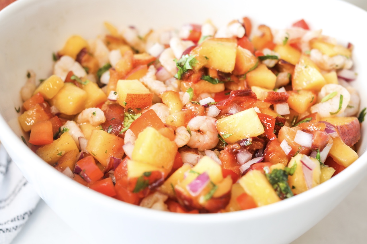 Peach Salsa with Shrimp Close Up Image in White Bowl with Black and White Decorative Towel on The Left Side for Styling.