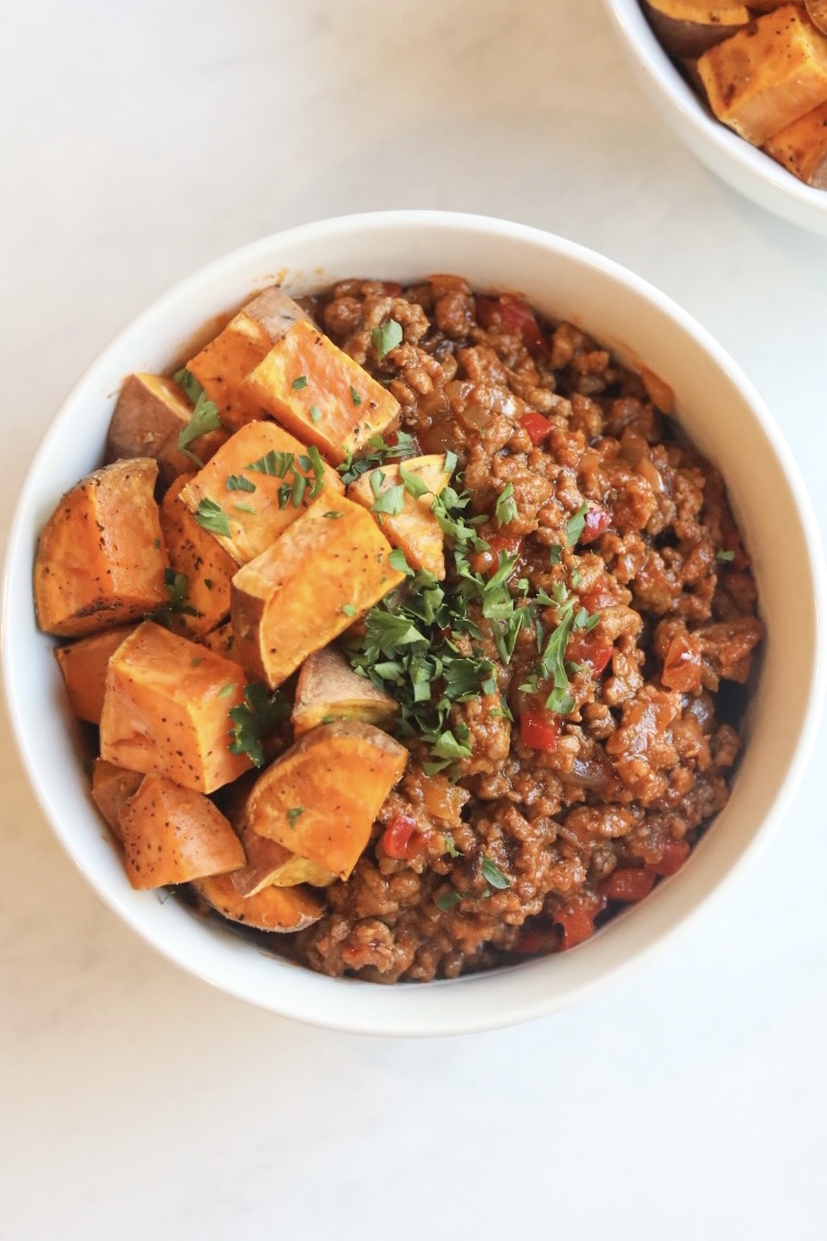 Bun-less Sloppy Joe in a bowl with cubed sweet potatoes. Topped with fresh parsley for garnish.