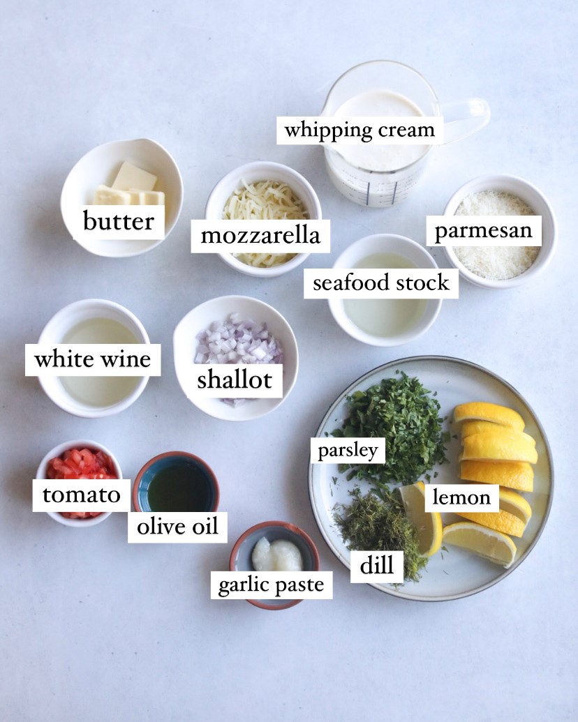 Lobster and Shrimp Ravioli Ingredients and Labels. Small white bowls with each ingredient in a separate bowl with butter, mozzarella, white wine, shallot, tomato, olive oil, garlic paste, parmesan and seafood stock. Clear measuring glass with whipping cream is also included in ingredients image.