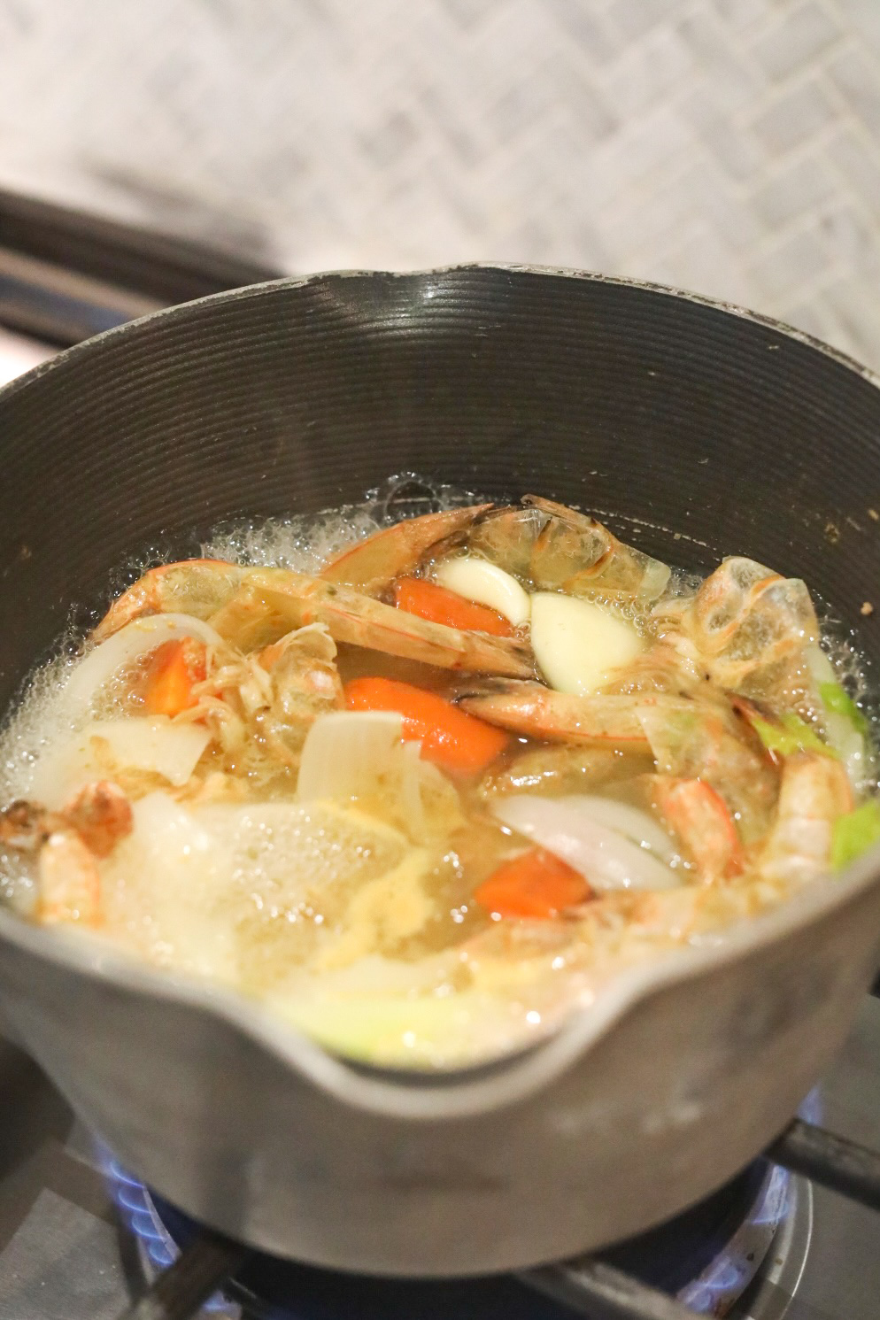 Seafood Stock in a gray sauce pot boiling.