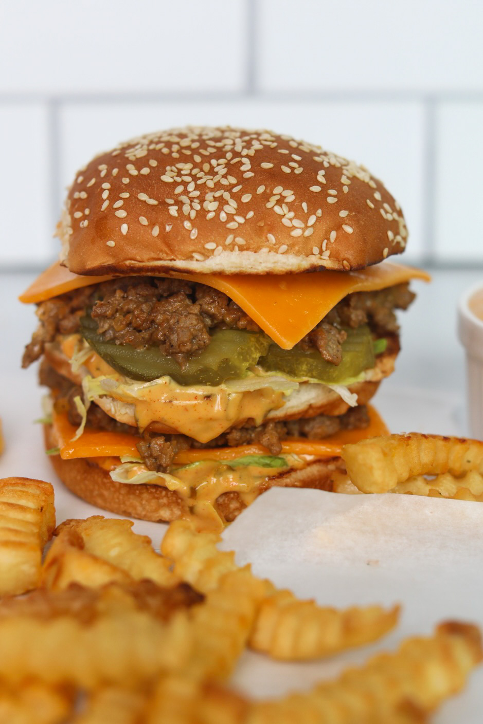 Big Mac Sloppy Joe image with stacked burger that looks similar to a traditional Big Mac but with ground beef "sloppy joe" texture and an extra slice of cheddar cheese. Fries are added for styling purposes.