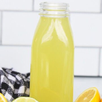 Homemade sour mix filled in a glass pint jar with sliced lemons and limes added for styling purposes. Black and white towel added for styling purposes.