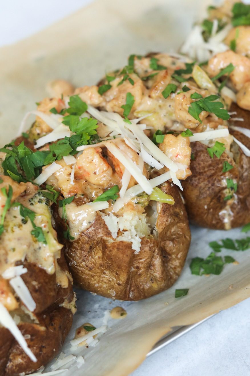 shrimp baked potato and broccoli Four baked potatoes baked and topped with Cajun shrimp cream sauce. Baked potatoes are topped with additional shredded cheese and fresh parsley.