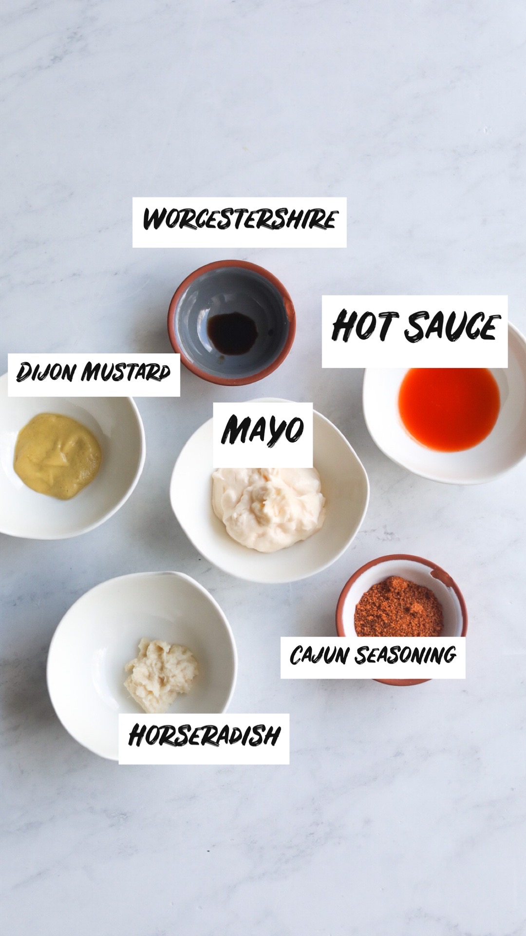 Salmon Cheesesteak Remoulade Sauce ingredients. Ingredients are filled in small bowls with mayo, hot sauce, horseradish, mayo, Dijon mustard, Cajun seasoning and Worcestershire sauce.