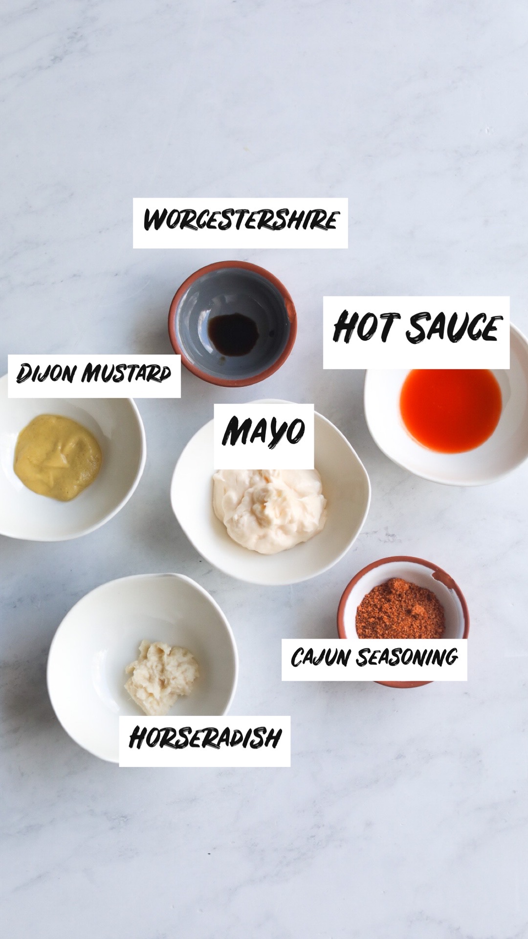 Salmon Cheesesteak Remoulade Sauce ingredients. Ingredients are filled in small bowls with mayo, hot sauce, horseradish, mayo, Dijon mustard, Cajun seasoning and Worcestershire sauce. 