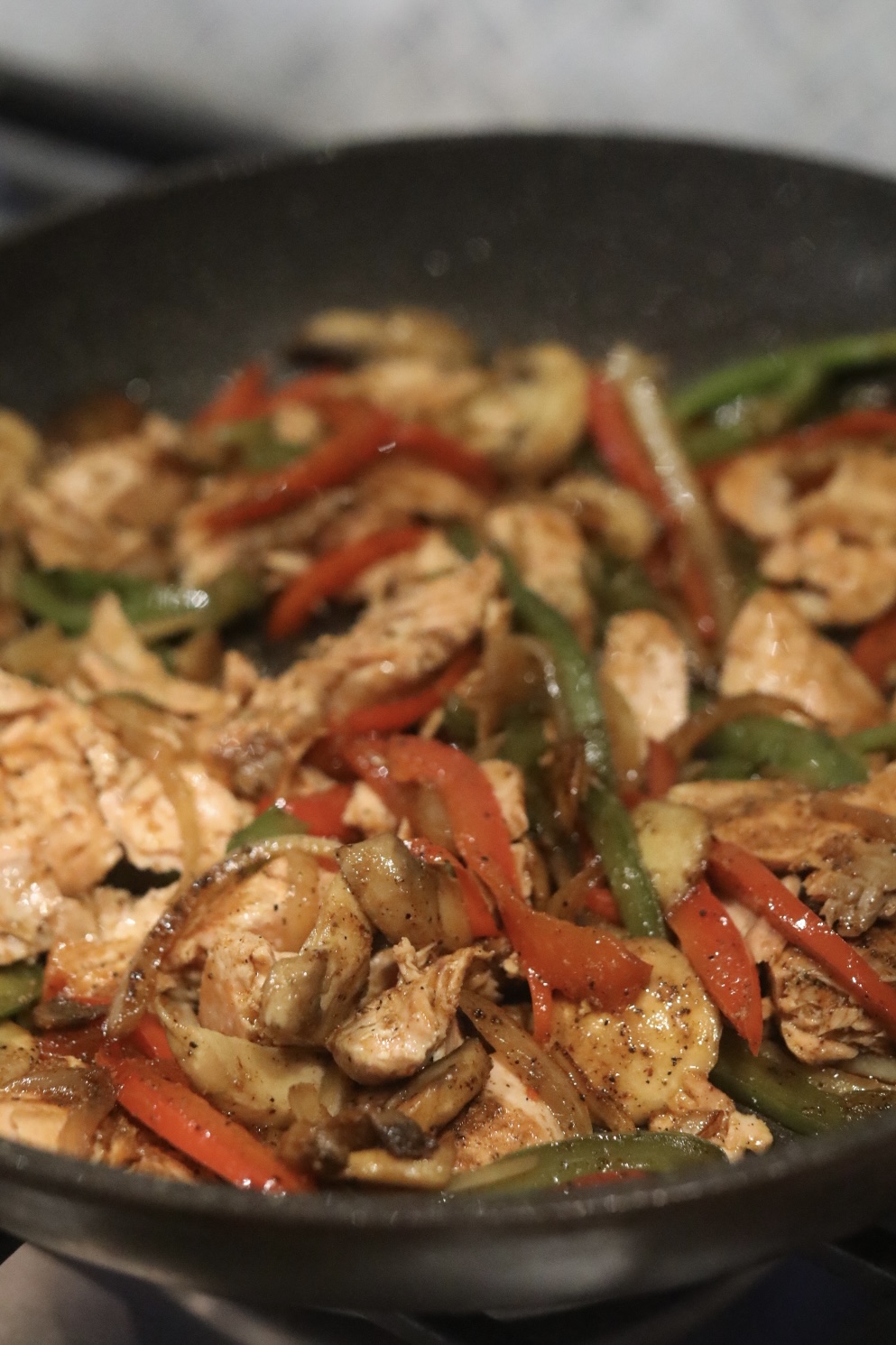 Salmon Cheesesteak filling ingredients in a black skillet.