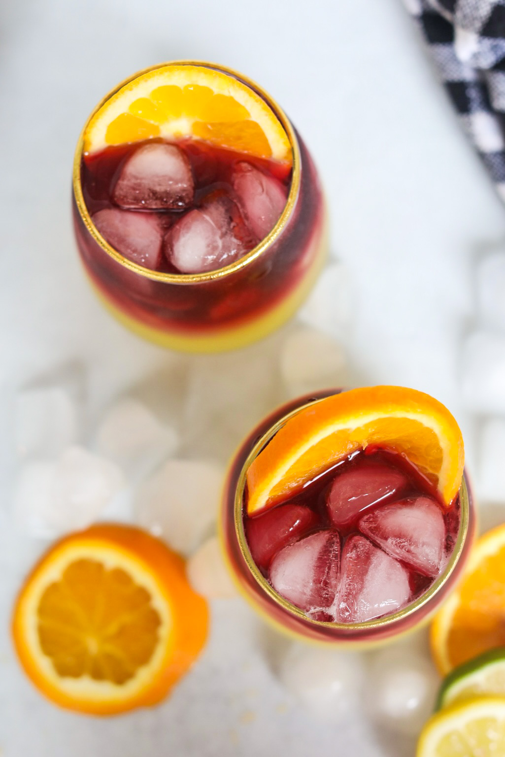Top-down shot of two glasses filled with sangria margarita. Orange slices are added into the glasses and on around the glasses for styling purposes.