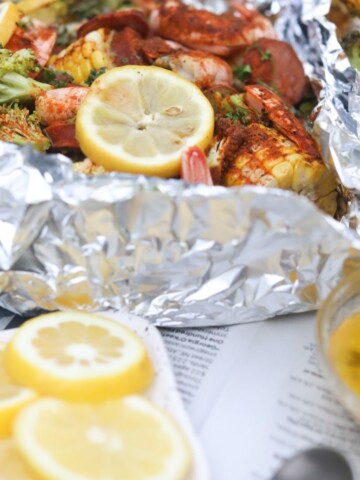 Shrimp foil packets with shrimp, potatoes and corn. Sliced lemons added for styling purposes.