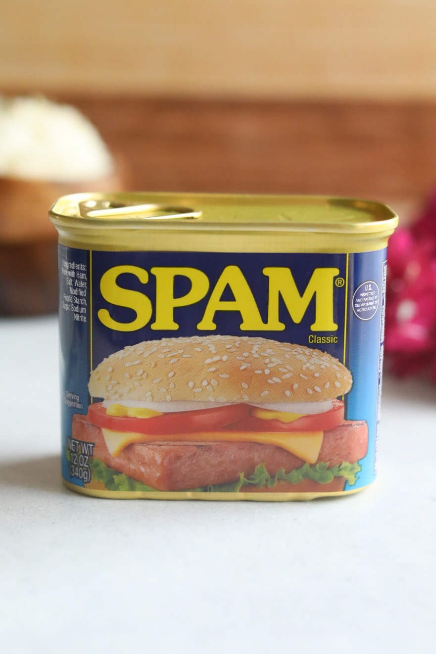 Image of canned spam. Blue aluminum can with yellow writing and image of sandwich on front of classic Spam packaging.