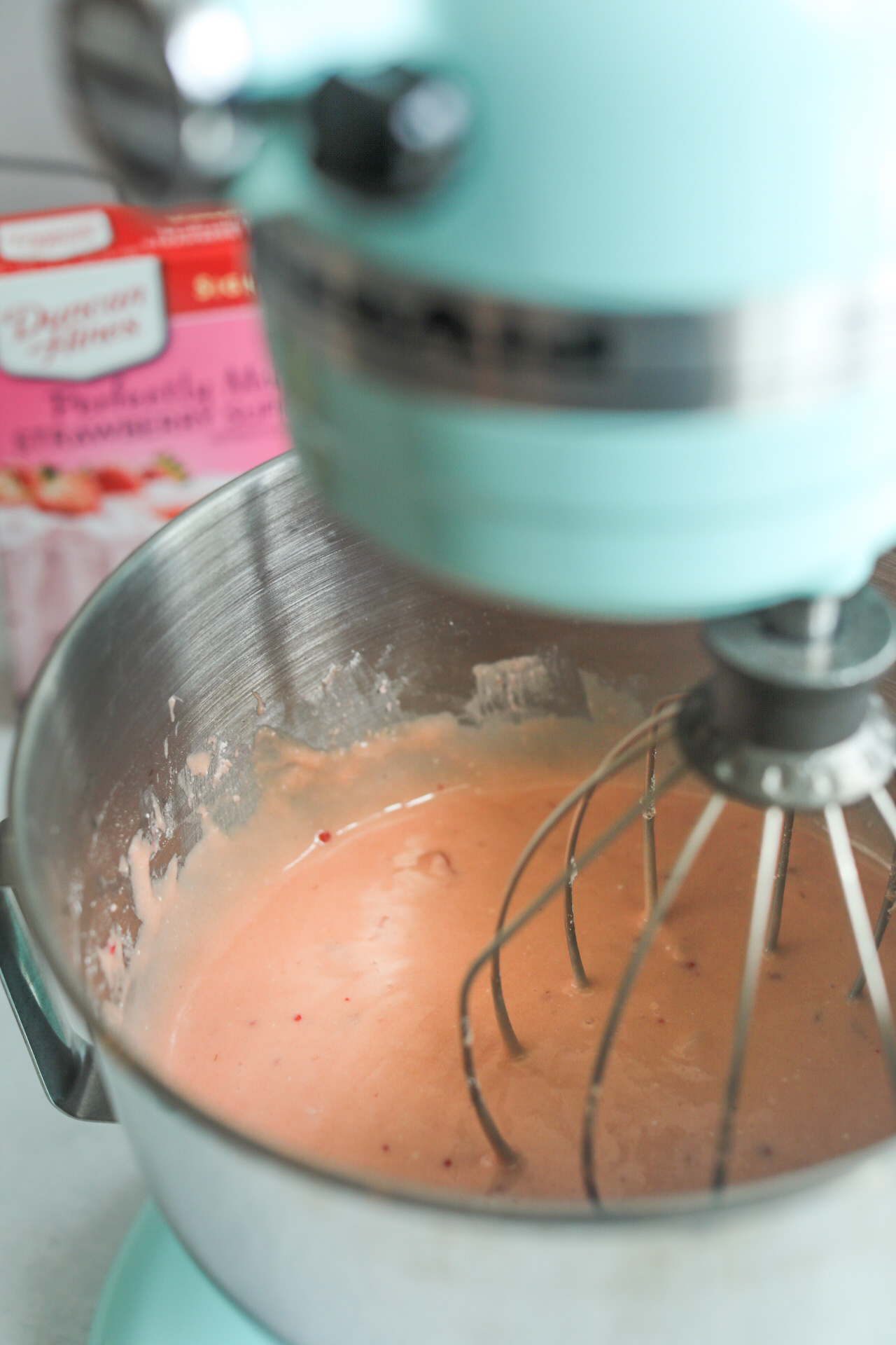 Strawberry cake pop cake mix blending in turquoise stand mixture.