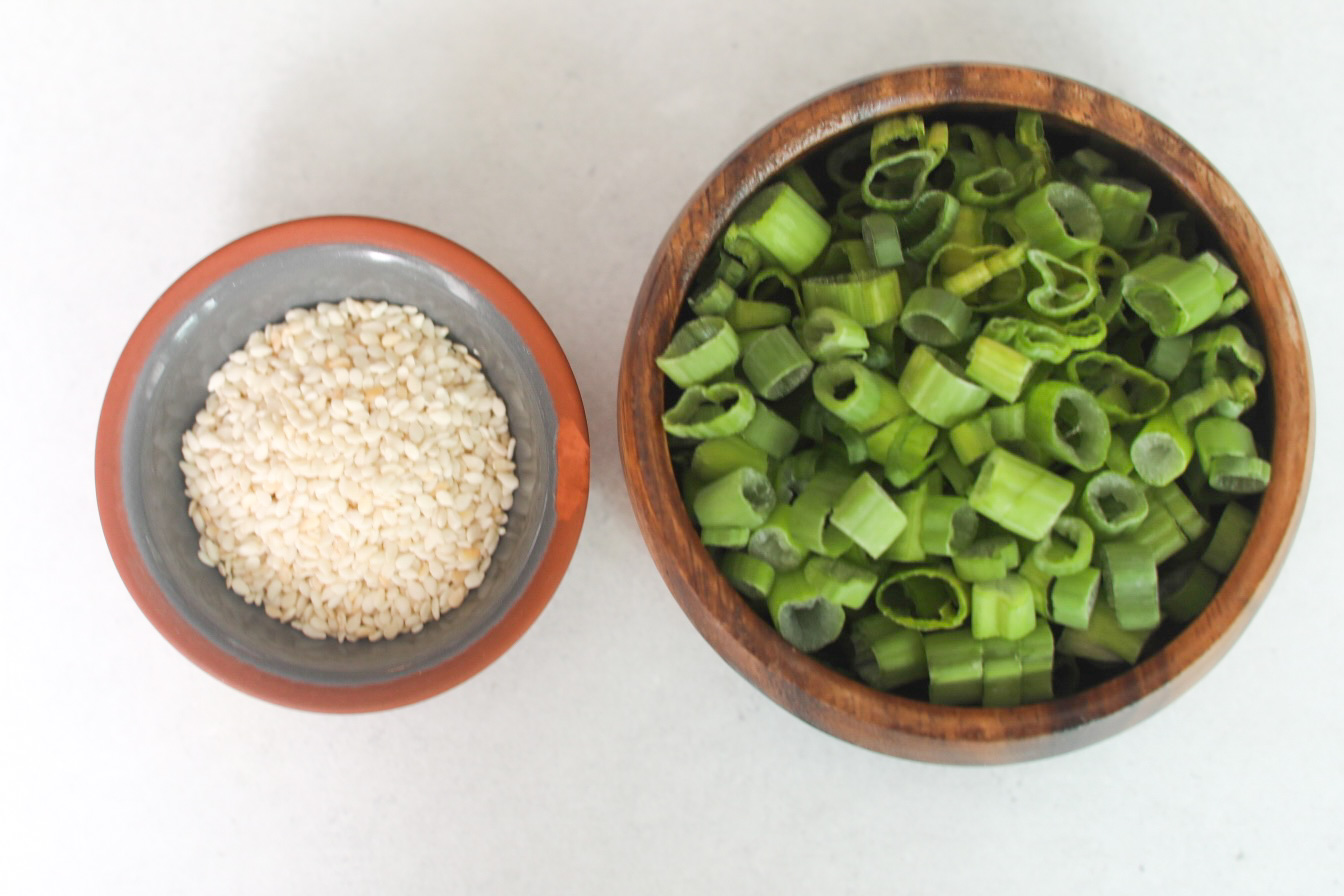 Spicy Chicken Teriyaki Ingredients. Chopped green onions and sesame seeds in small bowls.