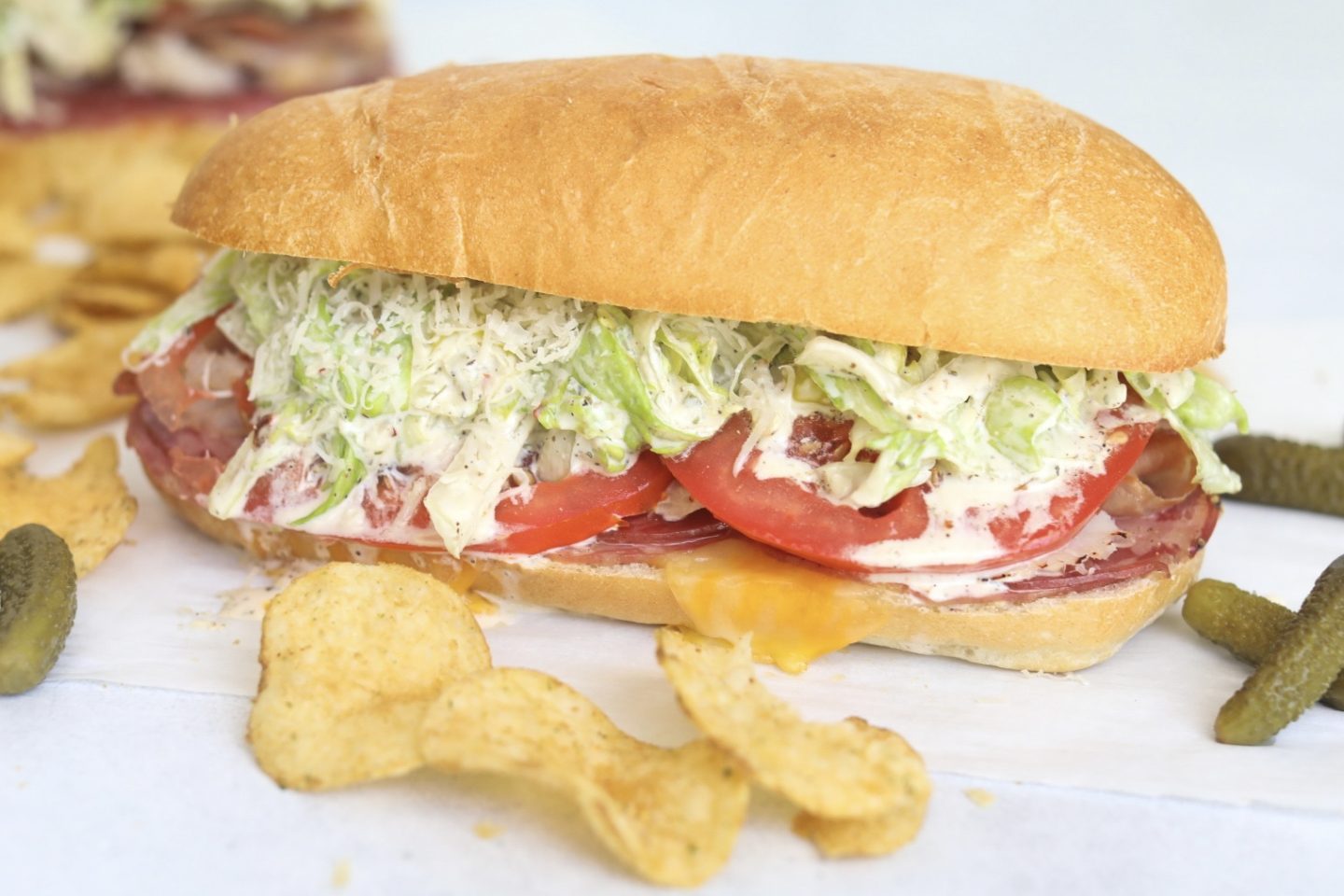 Italian Grinder Sub fully loaded with melted cheese, Italian meats, tomatoes and grinder salad. Chips and pickles added for styling purposes.