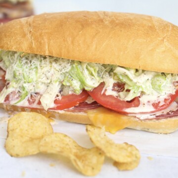 Italian Grinder Sub fully loaded with melted cheese, Italian meats, tomatoes and grinder salad. Chips and pickles added for styling purposes.