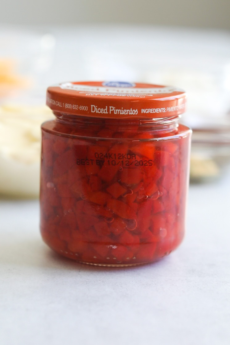 Small jar of canned red pimentos with orange top.