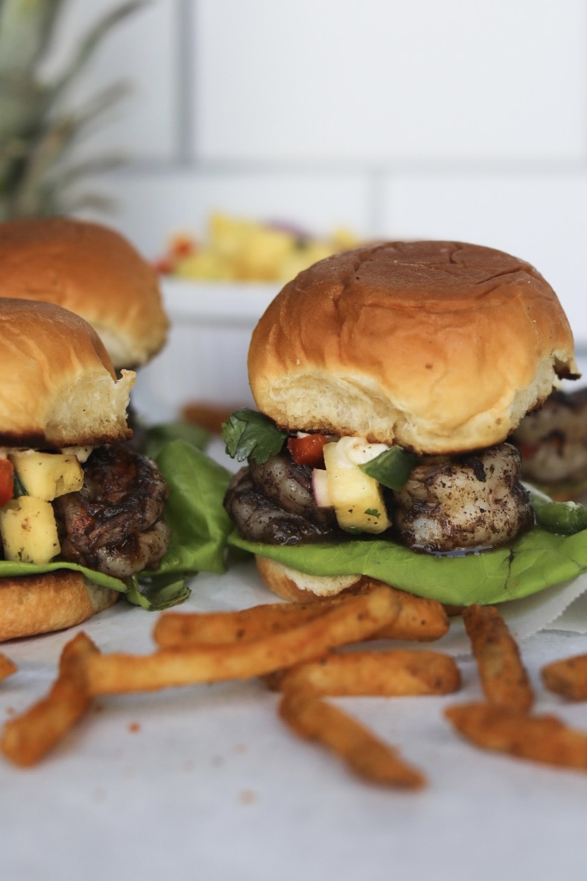 Finished recipe of jerk sliders styled with French fries and a pineapple added for styling purposes.