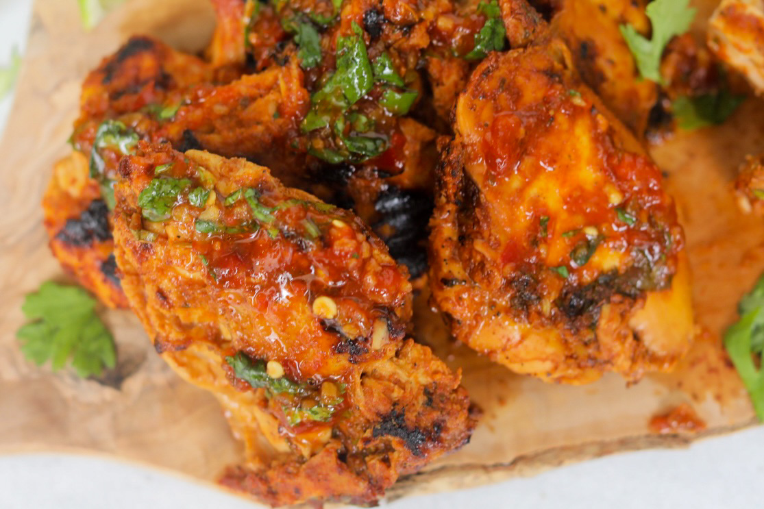 Chicken thighs cooked in pollo asado marinade served on a cutting board topped with chopped cilantro.