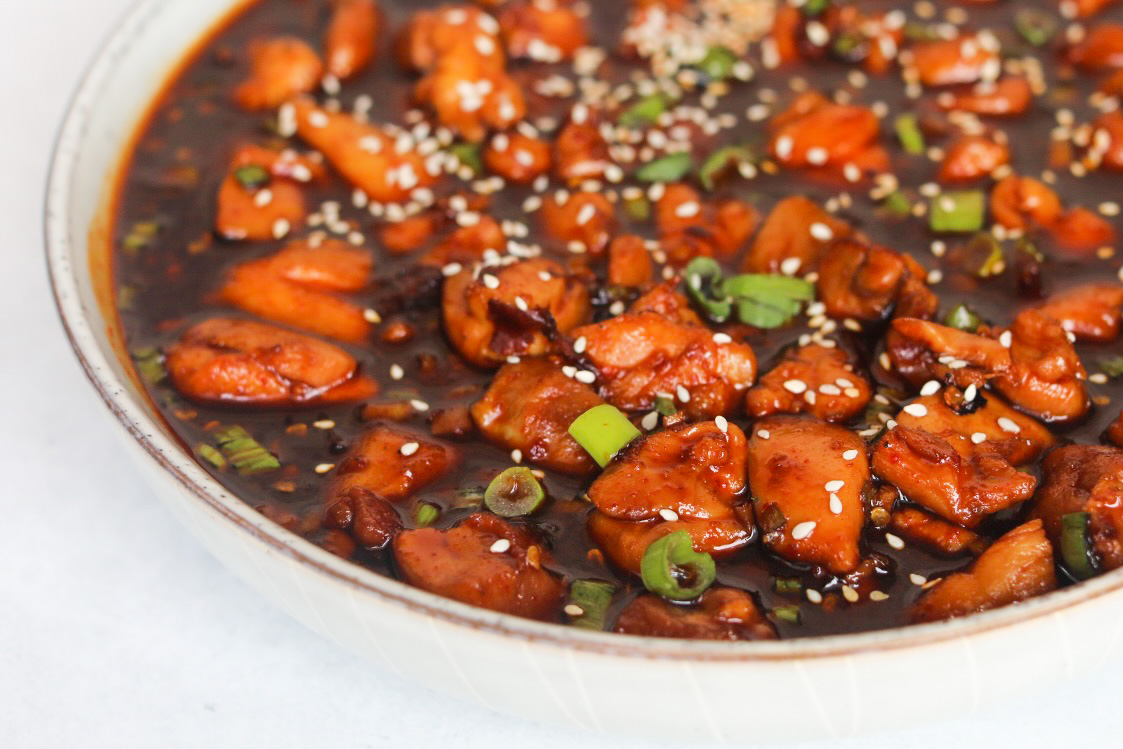 Spicy Chicken Teriyaki finished and plated in a serving bowl garnished with green onion and sesame seeds.