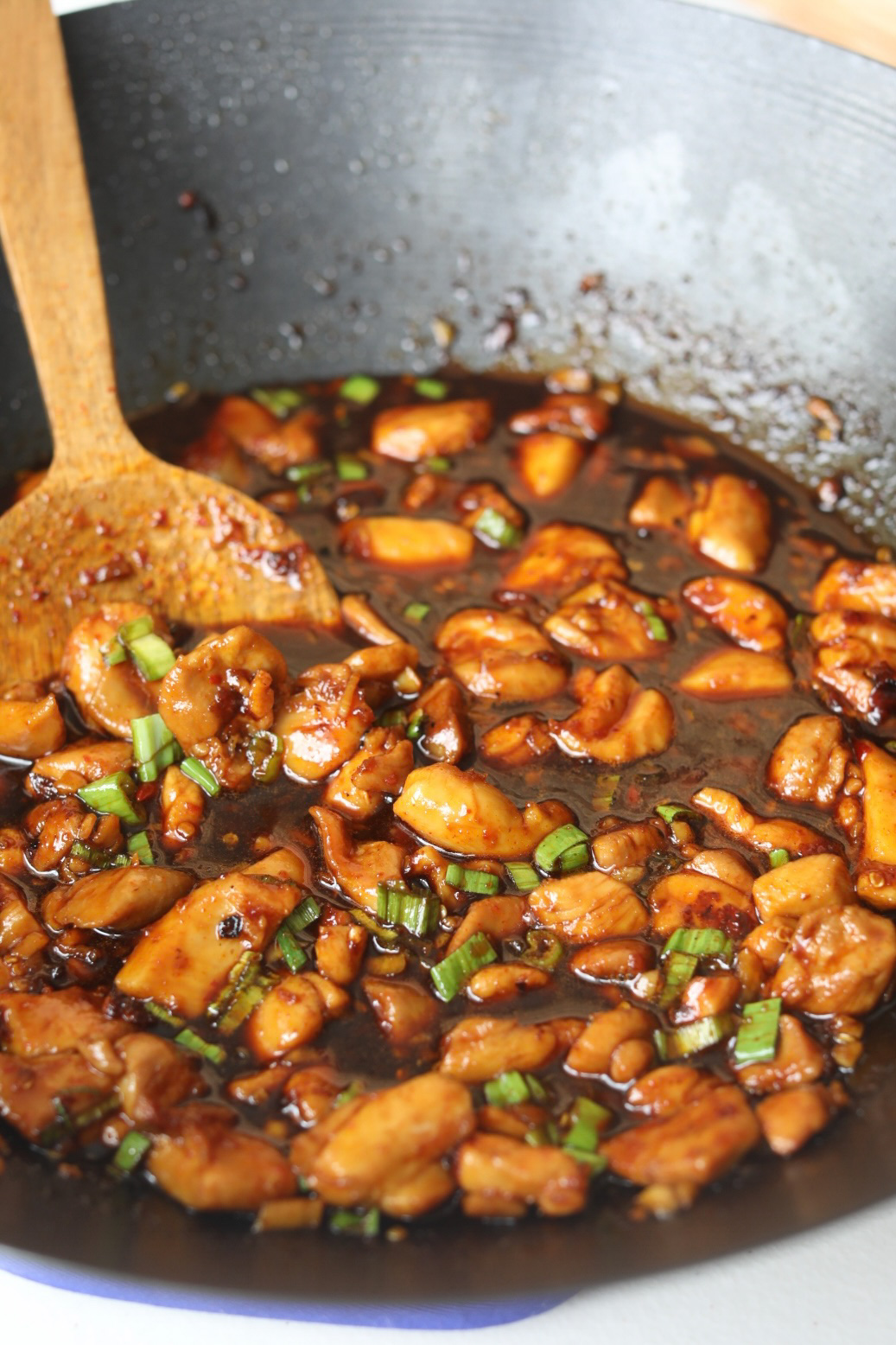 Spicy Chicken Teriyaki with cooked chicken thighs in dark brown sauce in a black wok.