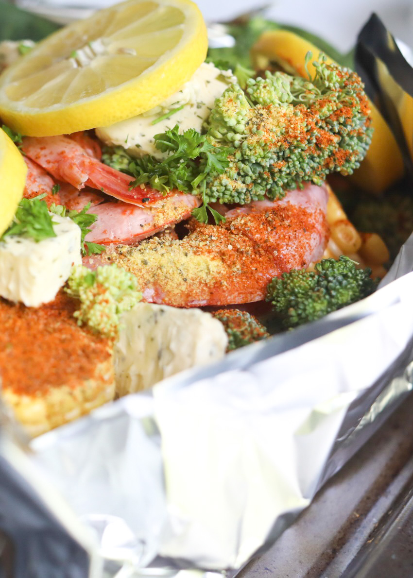 Closer angle of prebaked shrimp boil foil packets in aluminium foil in a baking sheet ready to be baked!