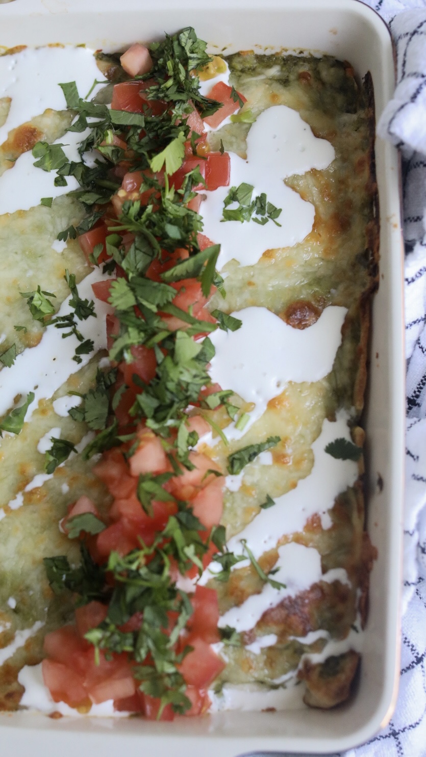 Chicken enchiladas with green sauce (poblano sauce), topped with gooey white cheese, sour cream, tomatoes and cilantro.