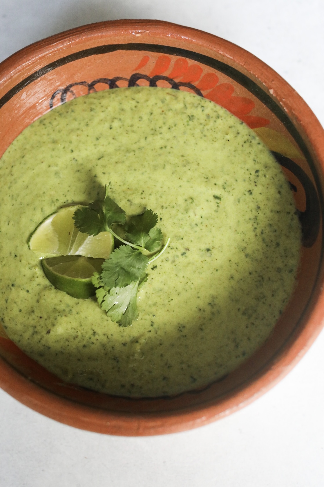 Poblano Cream Sauce (Culichi Salsa) in a clay bowl topped with cilantro and lime wedges.