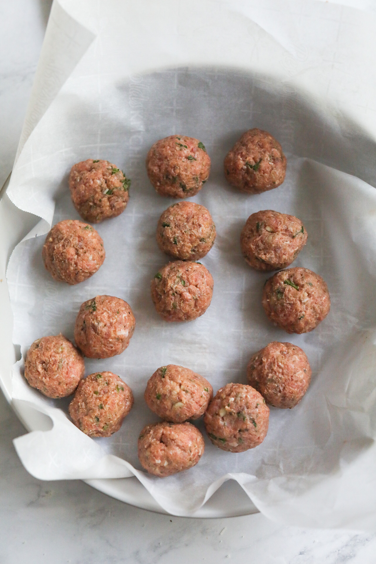 raw meatballs in a parchment lined pan 