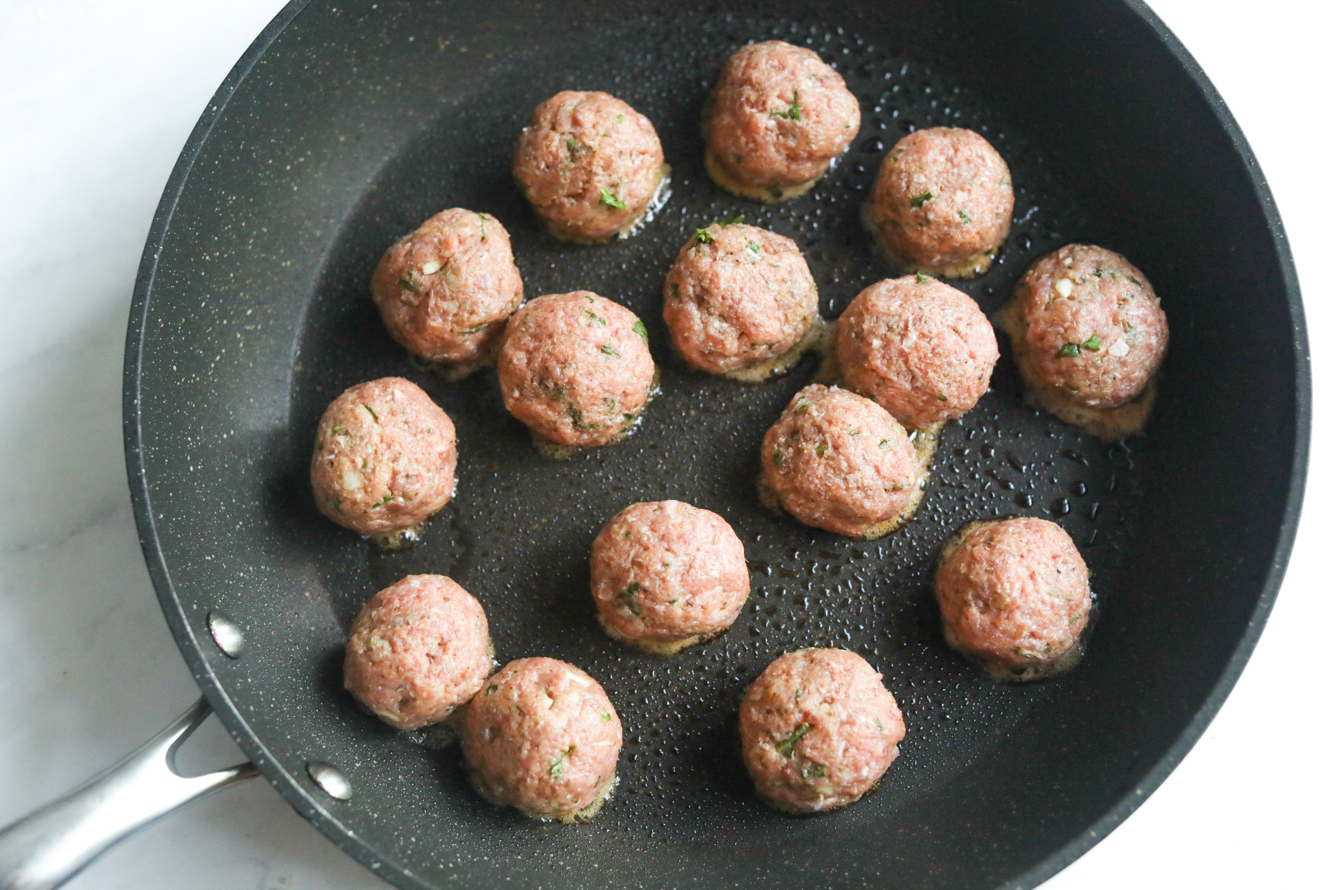 raw meatballs in a skillet