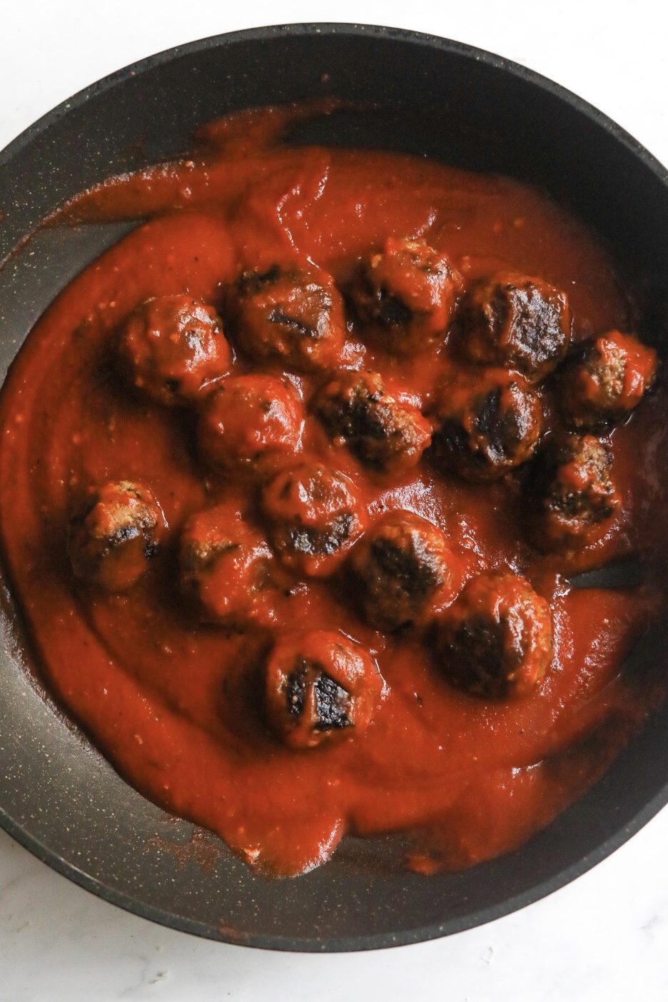 cooked meatballs in a skillet coated in marinara sauce