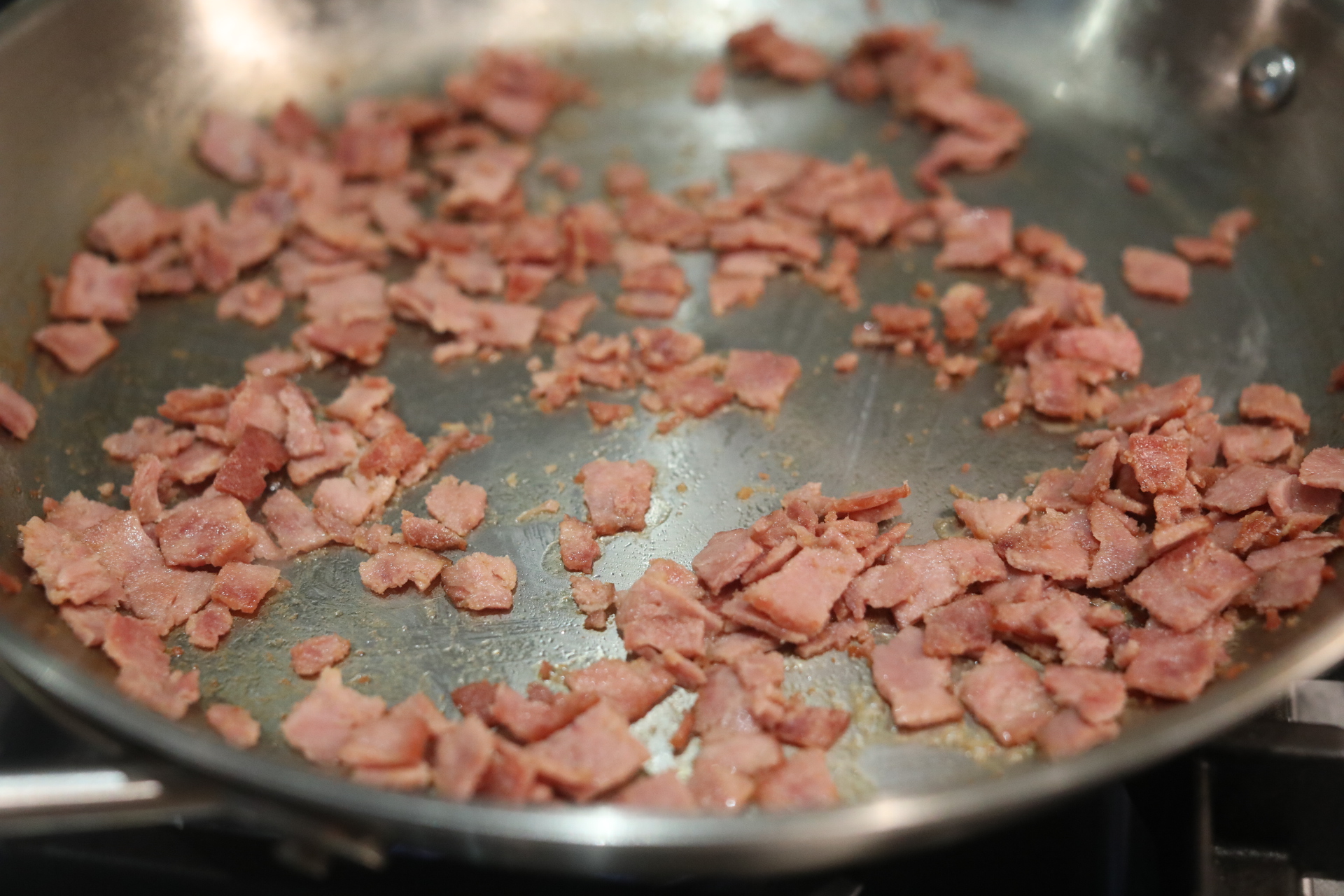 Turkey bacon sauteeing in metal pan.
