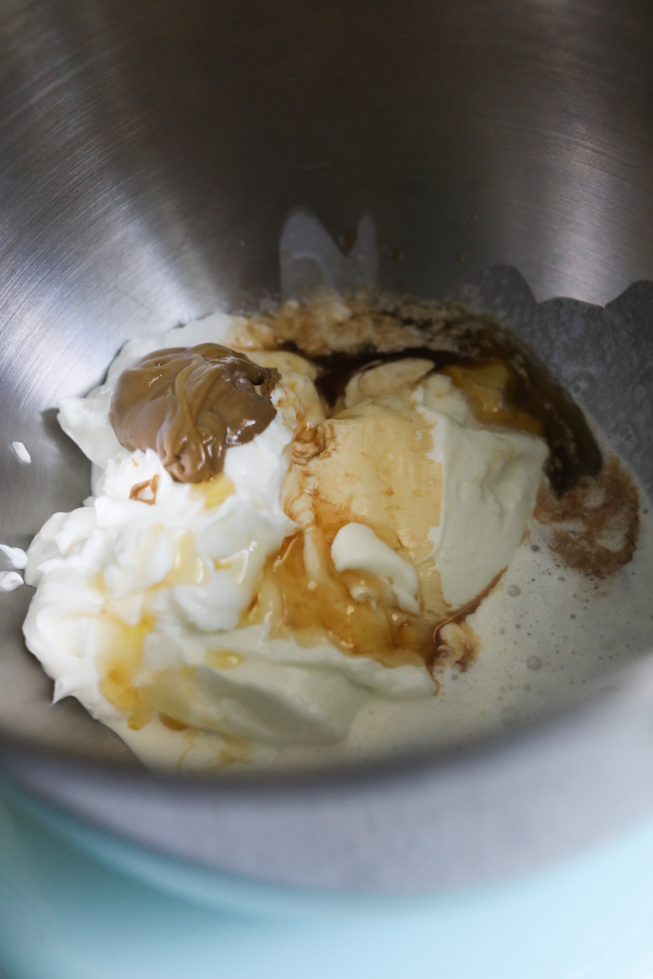In a metal stand mixer, whipped yogurt ingredients are poured in. Greek yogurt, vanilla extract, honey, sunflower butter and whipping cream. The contents are not mixed.