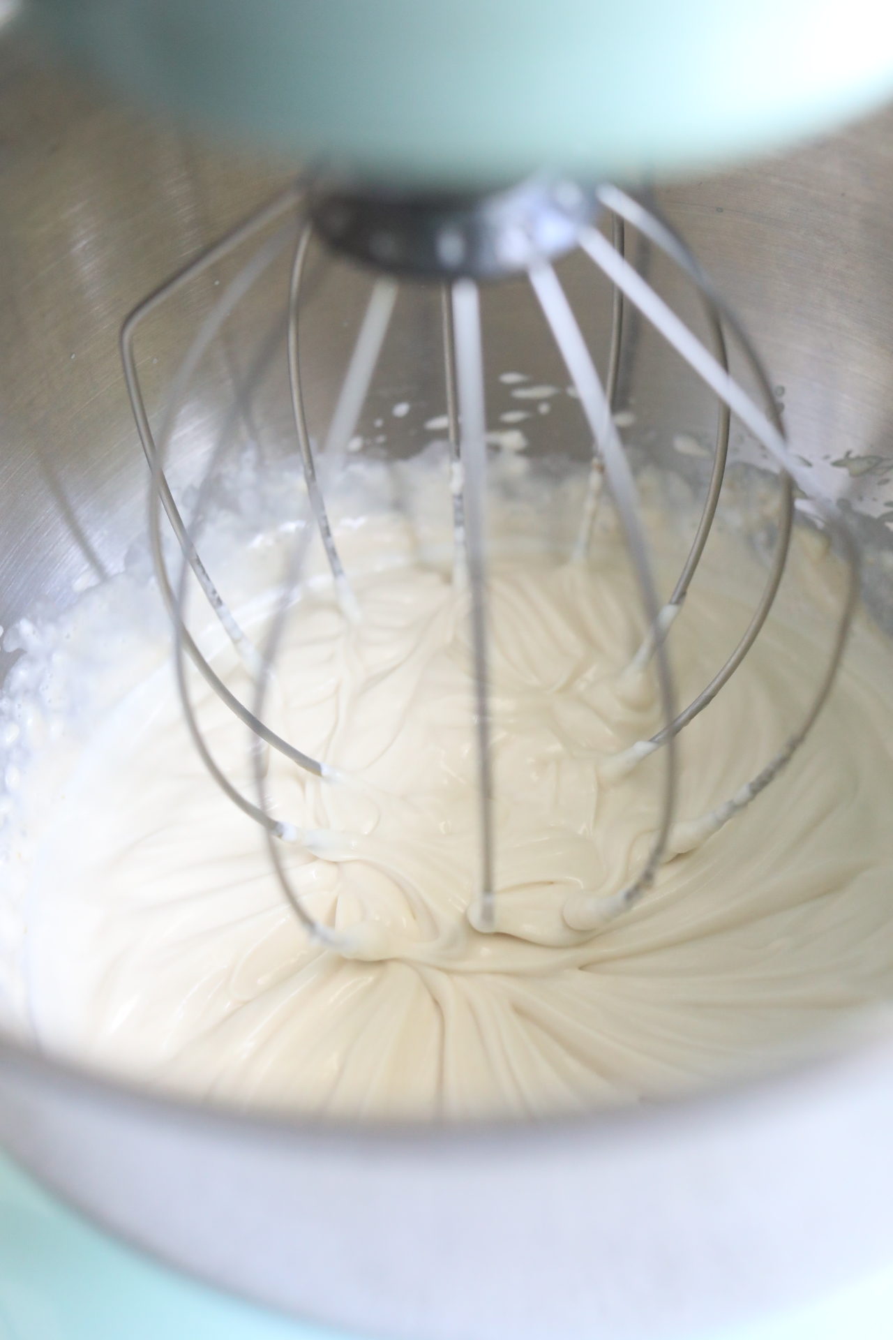 Whipped yogurt in stand mixer whipped showing fluffy consistency with whisk attached.