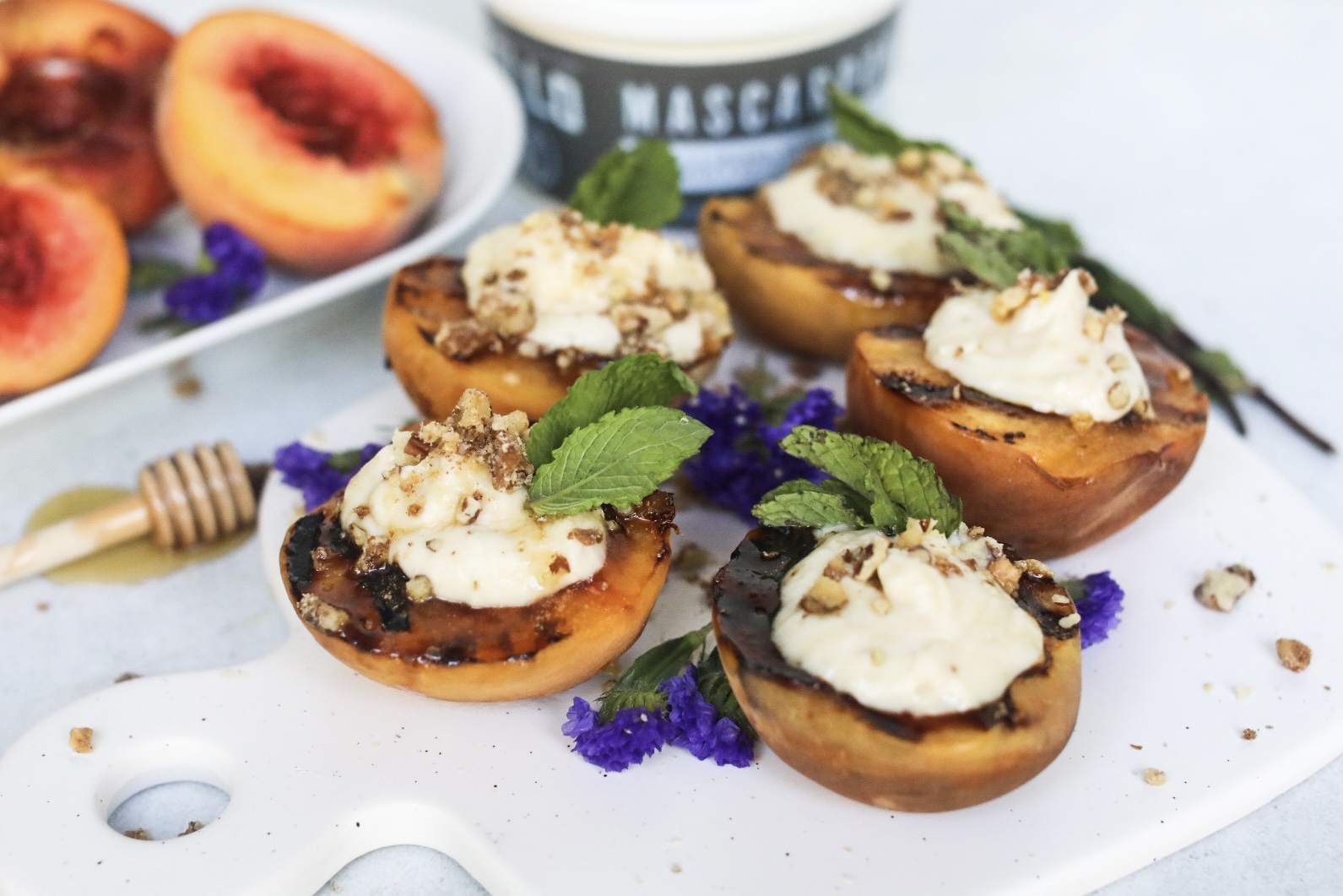 a plate of five grilled peaches with mascarpone with main ingredients in the background