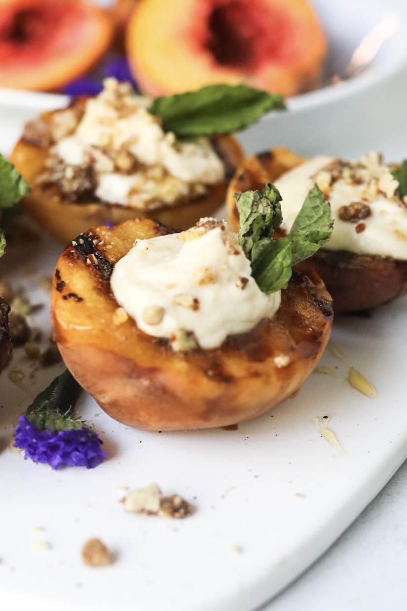 grilled peaches on stove close up view of grilled stonefruit topped with creamy cheese filling