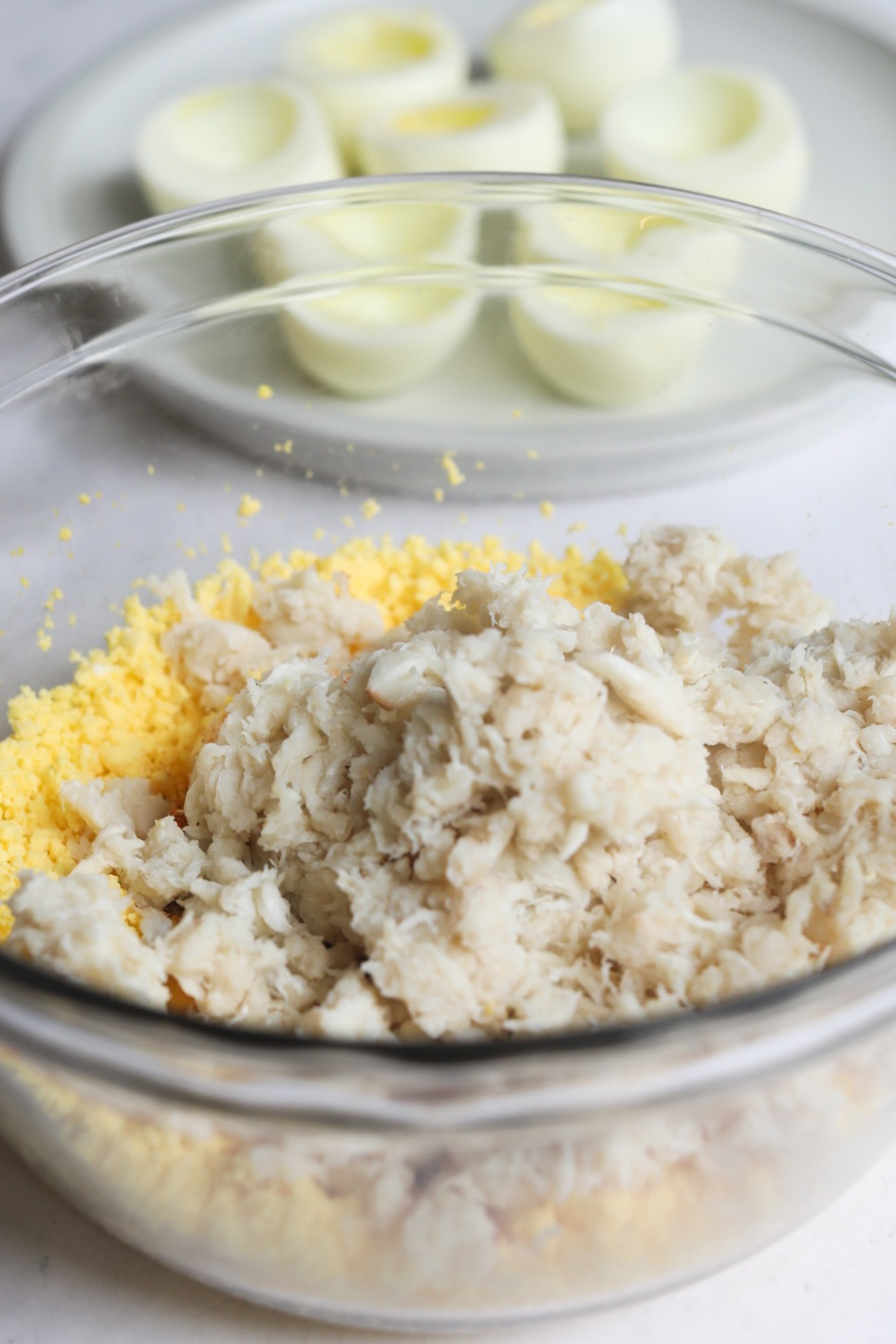 crab meat and boiled egg yolks in a bowl with boiled eggs whites in the background