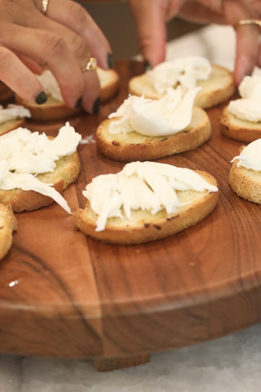 Toast point with toasted Italian style bread with burrata on a wooden charcuterie style board.