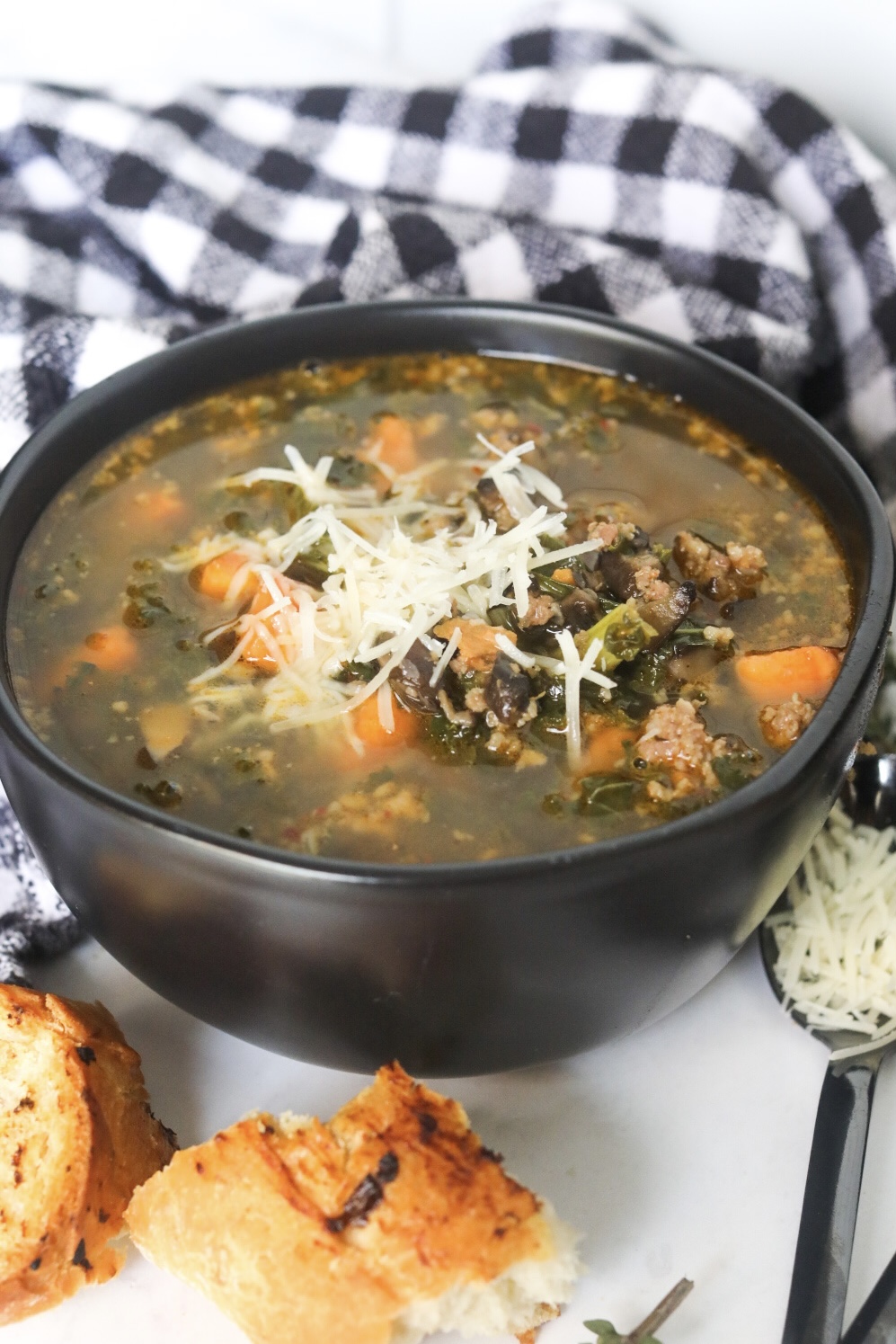 close up view of a bowl of sausage and potato soup topped with shredded parmesan