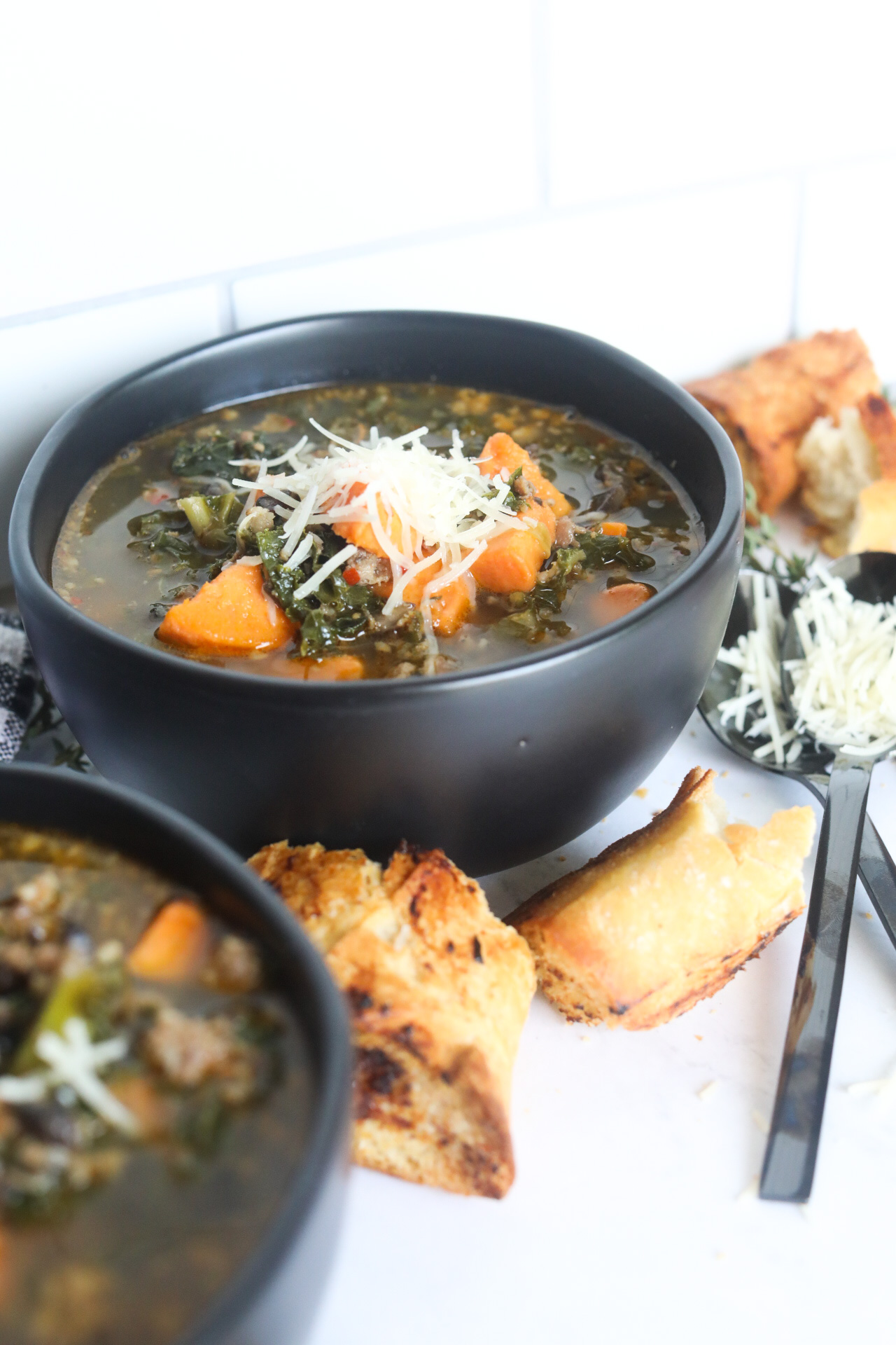 bowls of sausage and potato soup with bread