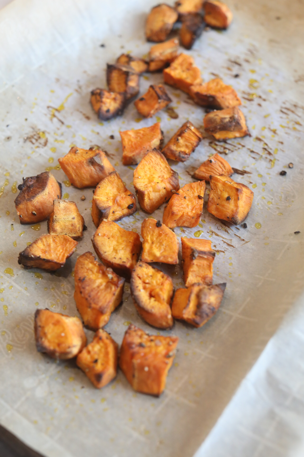Roasted sweet potatoes roasted on parchment paper cut into chunks