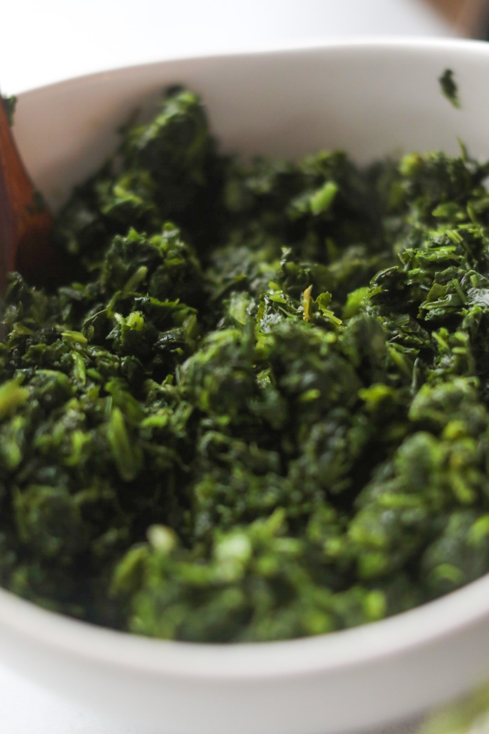 Cold spinach dip ingredients. Image shows frozen spinach thawed in a white bowl.